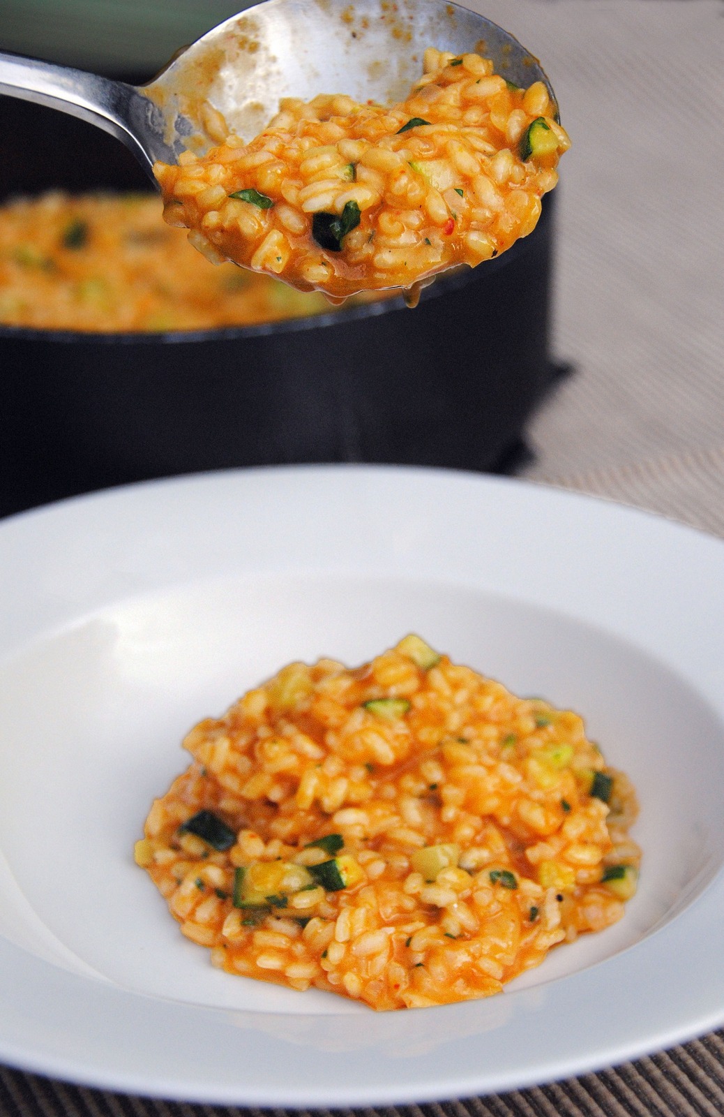 Yellow and Red Pepper Risotto with Zucchini Being Served from Black Pot